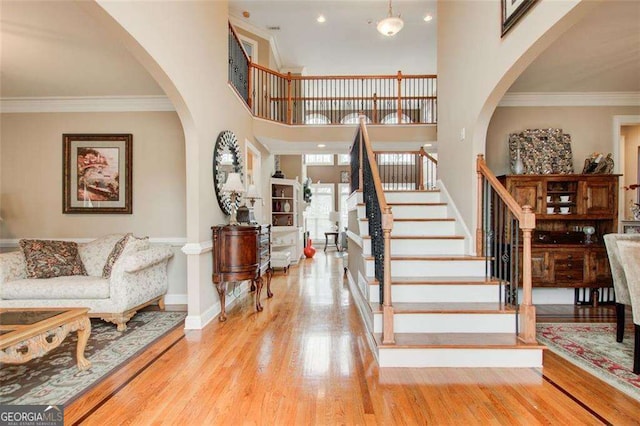 entryway with crown molding, light hardwood / wood-style flooring, and a high ceiling