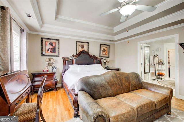 bedroom featuring ceiling fan, ornamental molding, a tray ceiling, and light hardwood / wood-style flooring