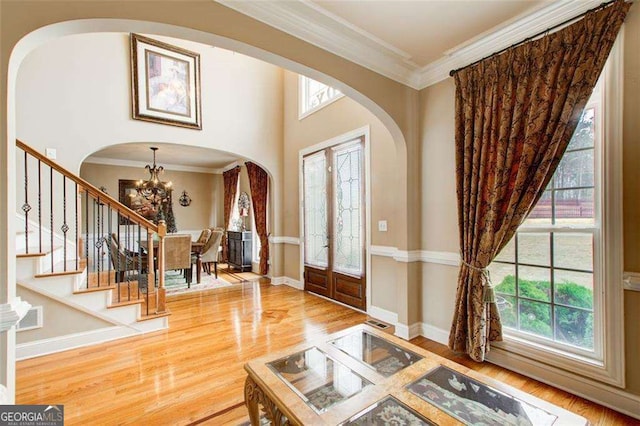 foyer entrance with hardwood / wood-style flooring, ornamental molding, and a notable chandelier