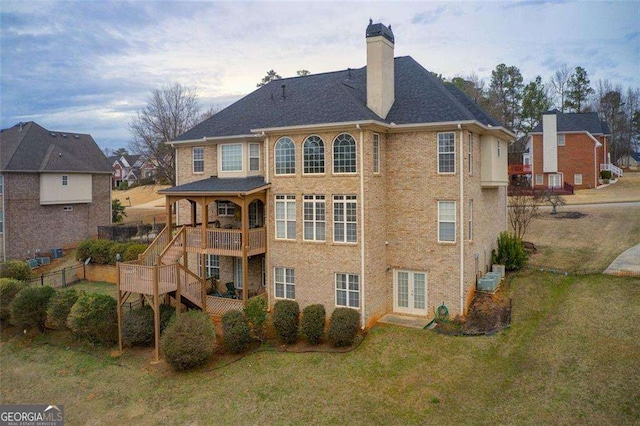 back of property with a deck and a lawn