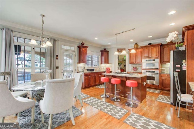 kitchen featuring a breakfast bar area, stainless steel appliances, a notable chandelier, a kitchen island, and decorative light fixtures