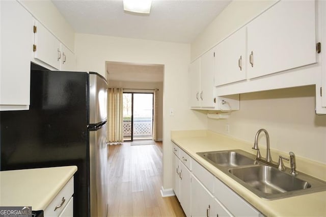 kitchen with stainless steel refrigerator, white cabinetry, light hardwood / wood-style floors, and sink