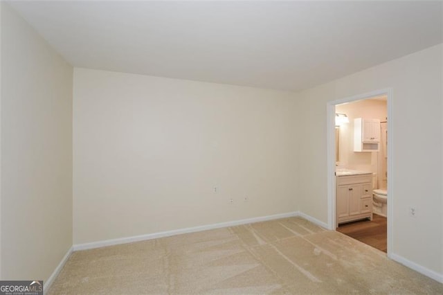 unfurnished bedroom with light colored carpet and ensuite bathroom