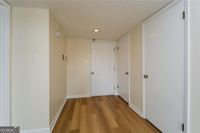 hallway with a textured ceiling and light wood-type flooring