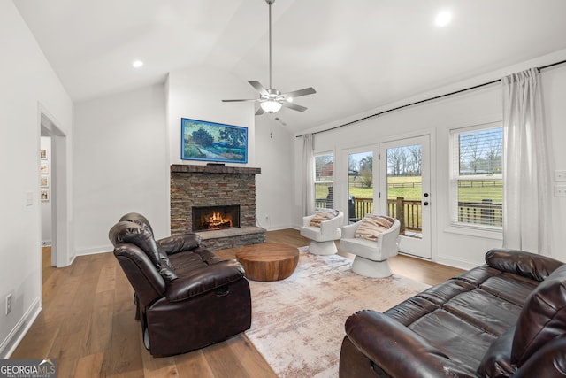 living room featuring hardwood / wood-style flooring, a stone fireplace, plenty of natural light, and lofted ceiling