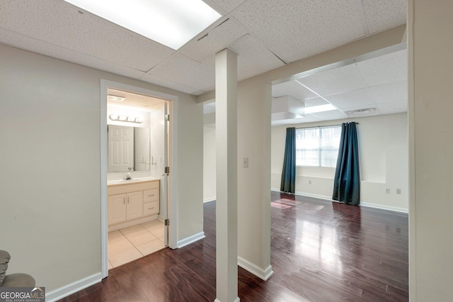 corridor with dark hardwood / wood-style flooring, sink, and a drop ceiling