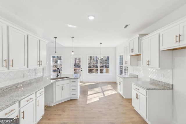 kitchen with white cabinetry, sink, pendant lighting, and kitchen peninsula