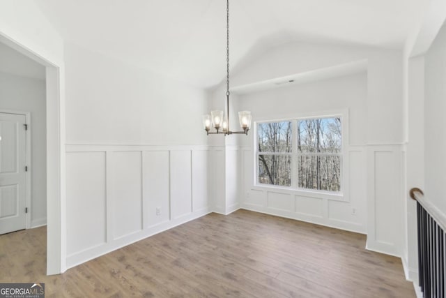 unfurnished dining area with vaulted ceiling, light hardwood / wood-style flooring, and a notable chandelier