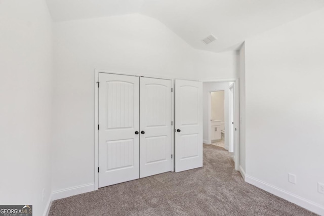 unfurnished bedroom featuring vaulted ceiling, light colored carpet, and a closet