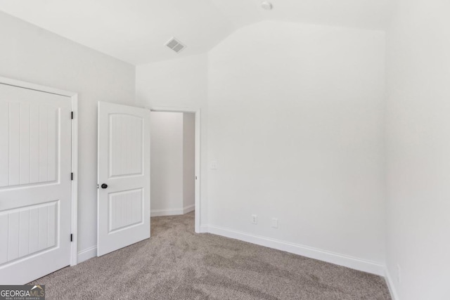 unfurnished bedroom featuring vaulted ceiling and light colored carpet