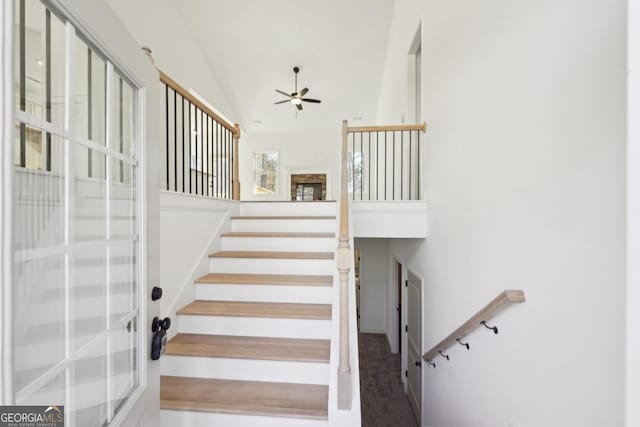 stairway with carpet floors, high vaulted ceiling, and ceiling fan