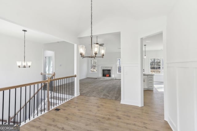 hallway featuring lofted ceiling, an inviting chandelier, and light hardwood / wood-style flooring