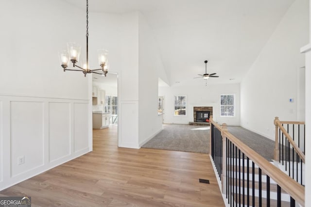 hallway with high vaulted ceiling, an inviting chandelier, and light hardwood / wood-style floors