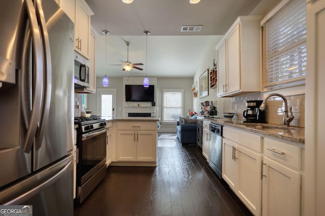 kitchen featuring sink, light stone counters, appliances with stainless steel finishes, ceiling fan, and white cabinets