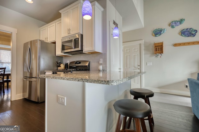 kitchen with white cabinetry, stainless steel appliances, decorative light fixtures, and a breakfast bar