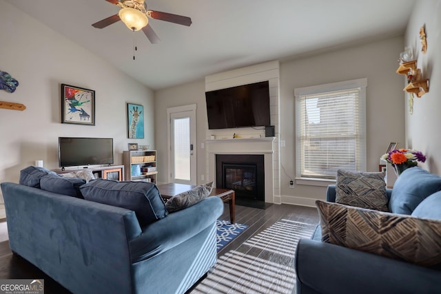 living room featuring vaulted ceiling, a healthy amount of sunlight, a fireplace, and dark hardwood / wood-style flooring
