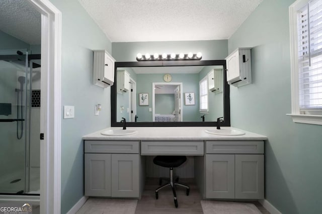 bathroom with vanity, a shower with shower door, and a textured ceiling