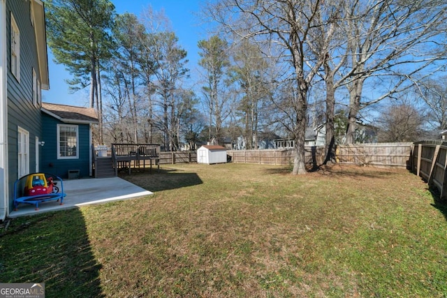 view of yard with a shed, a wooden deck, and a patio