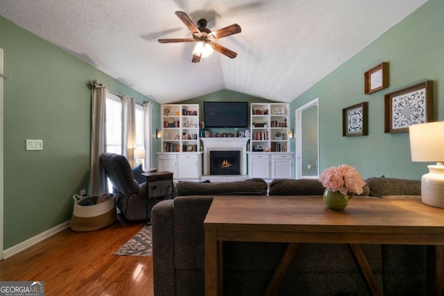 living room featuring ceiling fan, lofted ceiling, wood-type flooring, and a textured ceiling