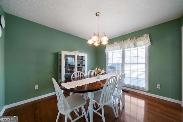 dining space featuring a textured ceiling, a notable chandelier, and dark hardwood / wood-style flooring