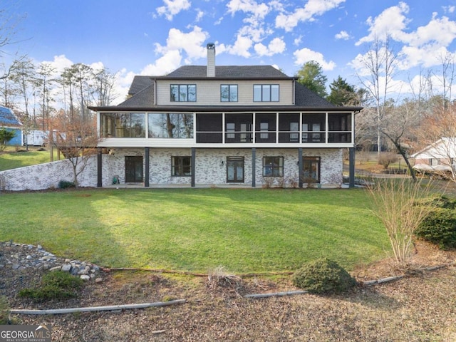 rear view of house with a yard, a chimney, and a sunroom