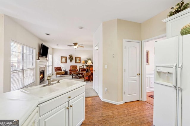 kitchen featuring sink, ceiling fan, white cabinetry, light hardwood / wood-style floors, and white fridge with ice dispenser