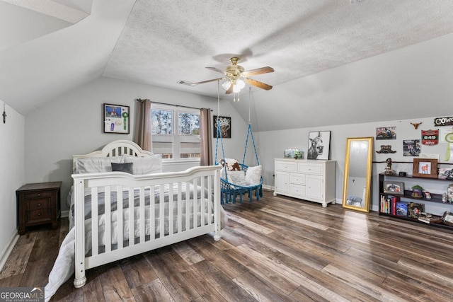 bedroom featuring vaulted ceiling, dark hardwood / wood-style floors, ceiling fan, and a textured ceiling