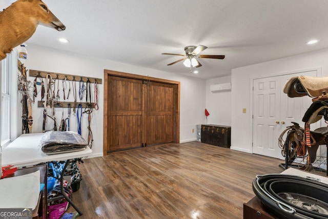 interior space featuring ceiling fan, hardwood / wood-style floors, a wall unit AC, and a textured ceiling