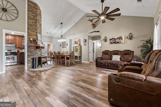 living room featuring ceiling fan, high vaulted ceiling, hardwood / wood-style floors, and a textured ceiling