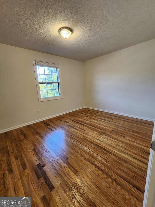 unfurnished room featuring dark hardwood / wood-style flooring and a textured ceiling