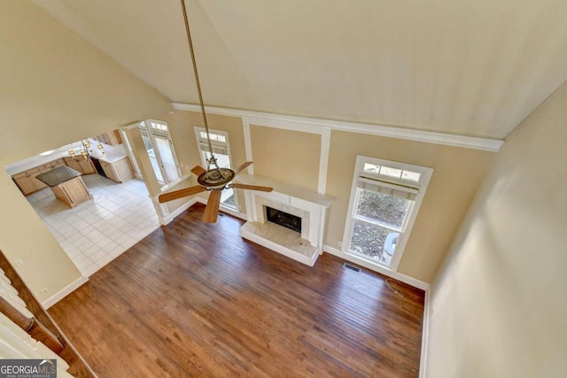 unfurnished living room featuring dark wood-type flooring, ceiling fan, a premium fireplace, and vaulted ceiling