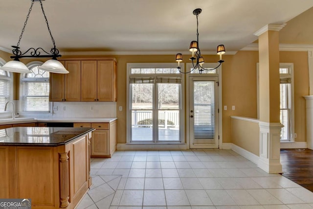 kitchen featuring hanging light fixtures, ornamental molding, dark stone counters, and ornate columns