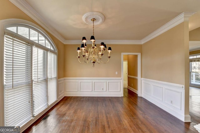 unfurnished dining area with an inviting chandelier, dark hardwood / wood-style flooring, ornamental molding, and a healthy amount of sunlight