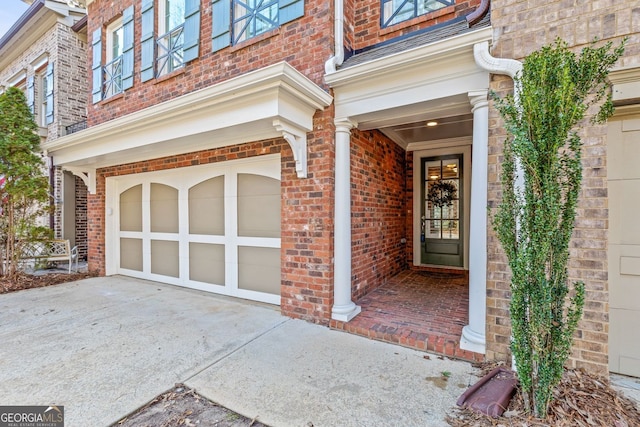 doorway to property featuring brick siding, driveway, and an attached garage