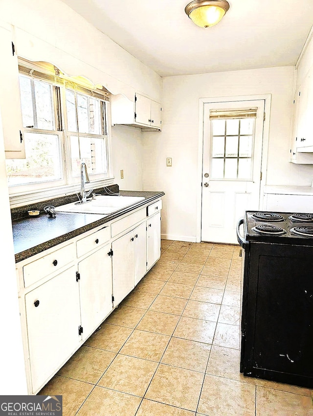 kitchen featuring black range with electric stovetop, light tile patterned floors, sink, and white cabinets