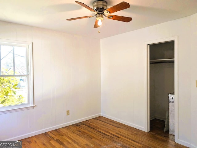 unfurnished bedroom with a closet, a spacious closet, and dark hardwood / wood-style floors