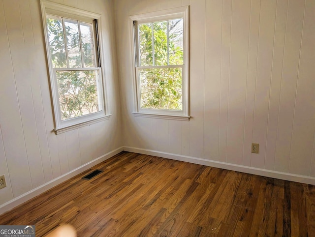 empty room with hardwood / wood-style floors and a healthy amount of sunlight