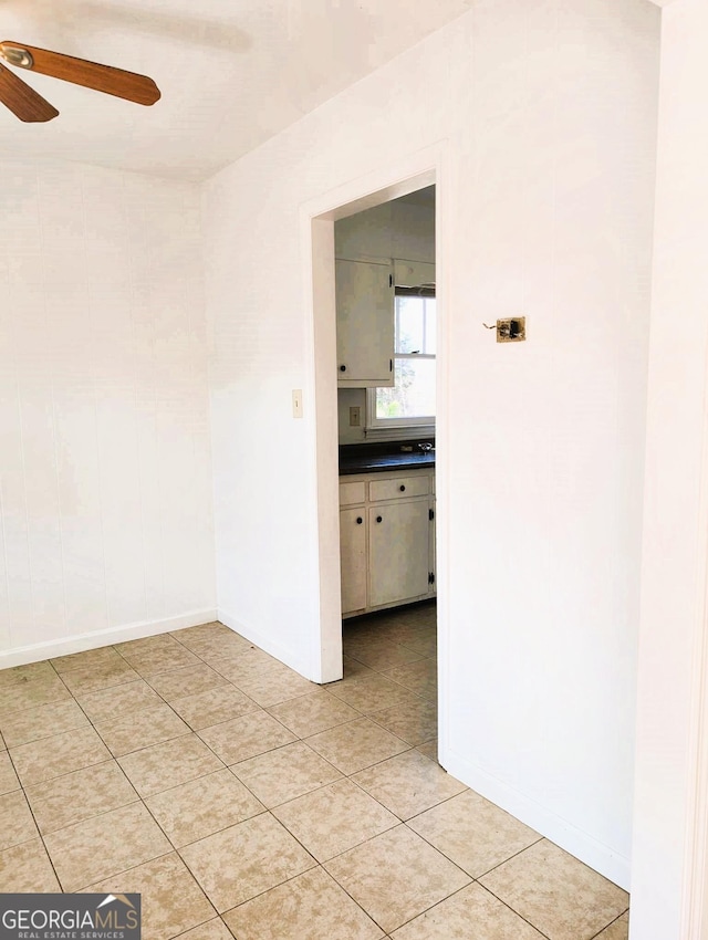 tiled empty room featuring ceiling fan