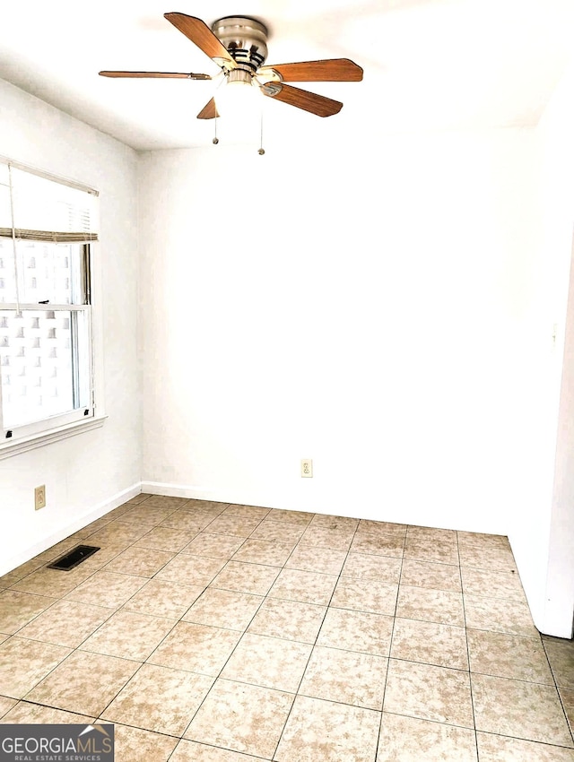 tiled spare room with ceiling fan