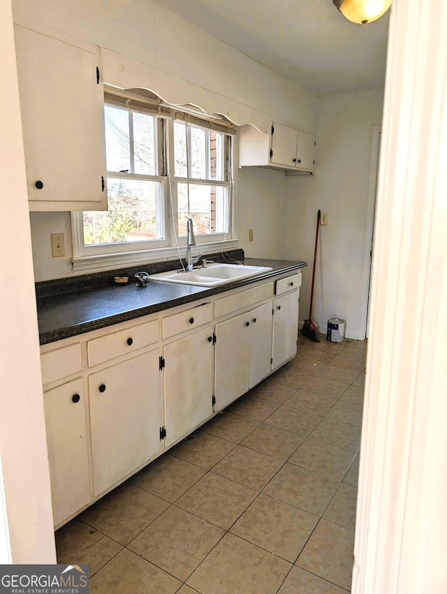 kitchen with white cabinetry, sink, and light tile patterned floors