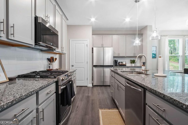 kitchen featuring stone countertops, gray cabinetry, a sink, appliances with stainless steel finishes, and dark wood-style floors