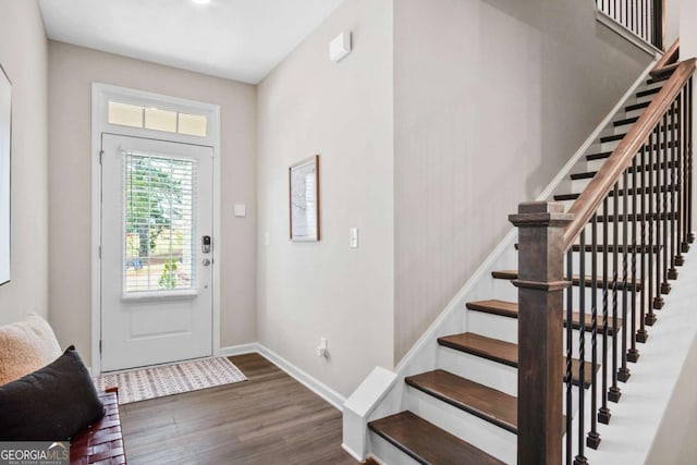 foyer entrance with stairway, baseboards, and wood finished floors