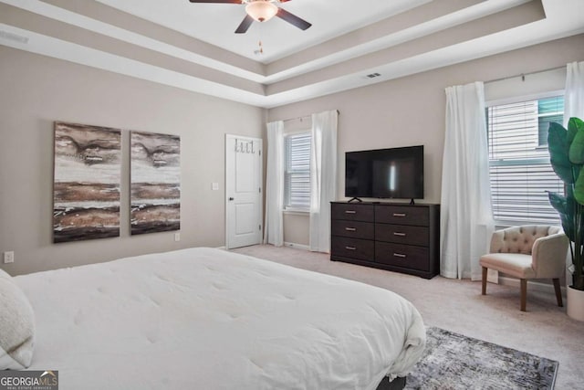 bedroom with light carpet, visible vents, and a raised ceiling