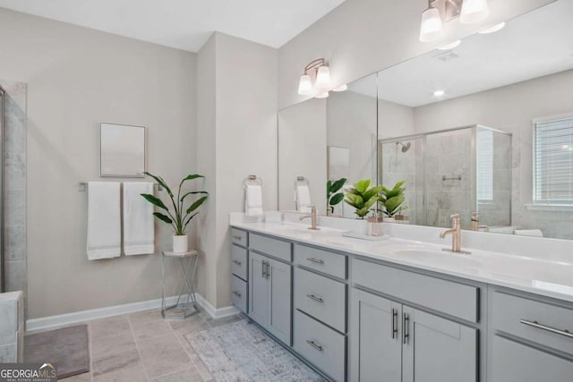 bathroom with double vanity, a sink, a shower stall, baseboards, and tile patterned floors