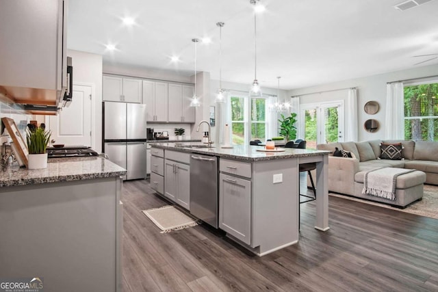 kitchen with a sink, open floor plan, appliances with stainless steel finishes, plenty of natural light, and a kitchen bar