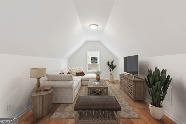 living area featuring lofted ceiling, wood finished floors, and baseboards