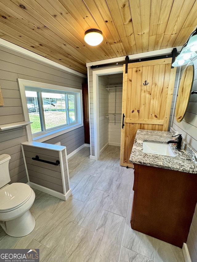 bathroom with wood walls, vanity, wooden ceiling, and toilet