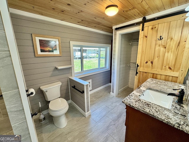 bathroom featuring vanity, wooden walls, wood ceiling, and toilet