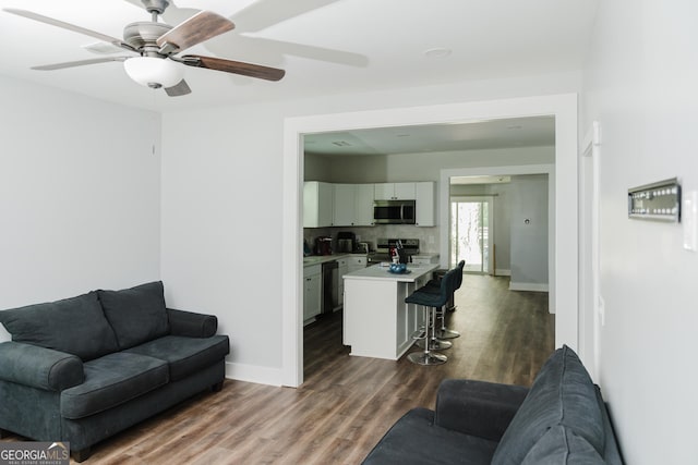 living room with ceiling fan and dark hardwood / wood-style floors