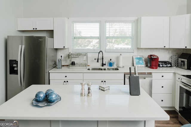 kitchen with sink, a center island, appliances with stainless steel finishes, white cabinets, and backsplash